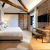 Sofraga Palacio in Ávila guest room with king bed, exposed beams, brick wall, and wall-mounted TV