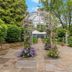 Stone Manor Boutique Inn in Lovettsville: garden walkway with floral arbor and white tented seating