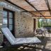 Le Rocche di Valiano in Vagliagli: stone patio with sun lounger, dining table, and pergola shade