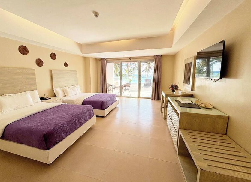 The Muse Beach Front Hotel Boracay room with two beds, sliding doors to balcony, and TV in Boracay