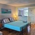 Studio 1 Motel Daytona Beach guest room with bed, lamps, sofa, ocean artwork and window view