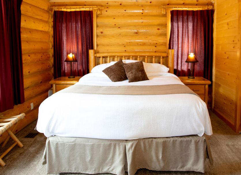 Beartooth Hideaway Inn & Cabins in Red Lodge, log cabin guest room with king bed and bedside lamps