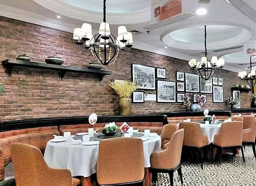 Beifang Langyue Hotel (Beijing Ganjiakou) restaurant with round tables, brick wall and chandeliers in Beijing