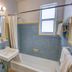 Ocean Beach Hotel in Miami Beach bathroom with blue tile, bathtub, sink, mirror and shower curtain