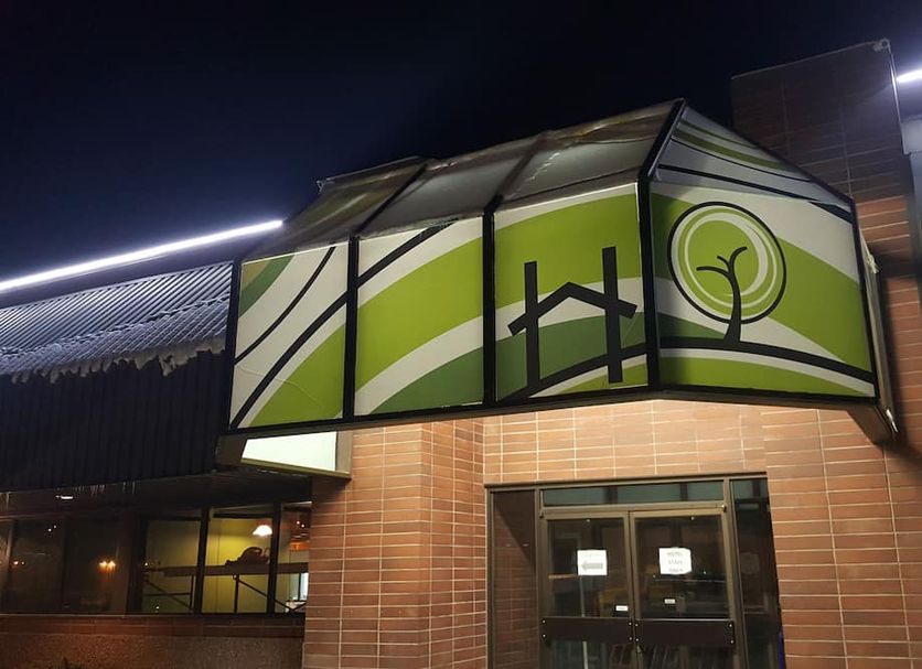 Home Away Inn in Drayton Valley exterior entrance with green canopy sign at night