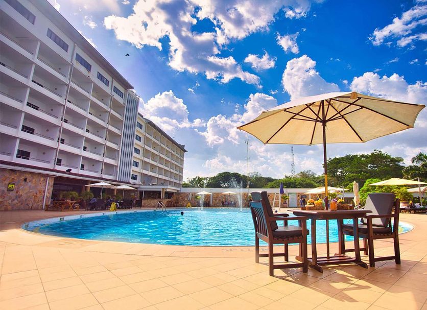 Golden Tulip Kumasi City in Kumasi: outdoor pool with patio table, umbrella and hotel building