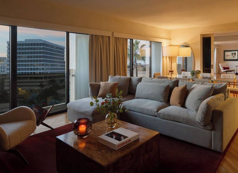 Sixty Beverly Hills suite with sofa, city-view windows, and warm lamp-lit living area