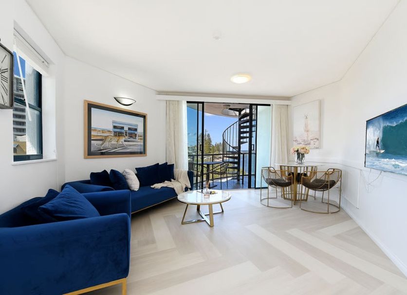 La Promenade Absolute Waterfront Apartments in Caloundra living room with blue sofa, balcony view and ocean glimpse