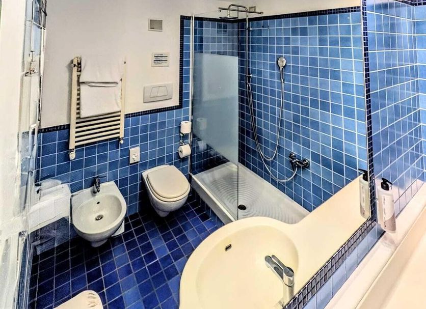 Hotel Express Aosta East bathroom in Pollein with blue tile, shower, bidet and sink