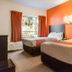 Motel 6 Surrey BC guest room with two beds, orange accent wall and window with curtains