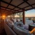 Gondwana Etosha Safari Lodge in Okaukuejo, covered veranda with sofa seating and sunset savanna view