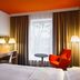 Park Inn by Radisson Frankfurt Airport guest room with orange chair, desk, TV and window in Frankfurt am Main