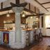 Vettonia Ávila hotel bar with wooden stools, hanging lights and stone column centerpiece