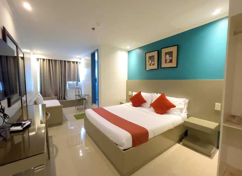 Legazpi Tourist Inn, Legazpi City room with bed, wall-mounted TV, desk, and teal accent wall