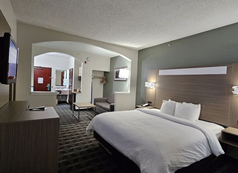 Quality Inn & Suites Irving Dfw Airport South room with king bed, seating area, and TV in Irving