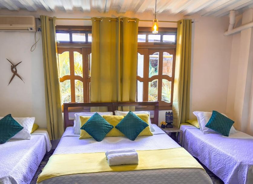Ecohotel El Refugio Boutique in Leticia: three beds with green pillows in a bright guest room
