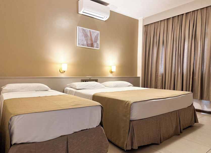 San Rafael Comfort Class Hotel in Foz do Iguaçu: twin beds with beige curtains and wall sconces