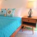 Waterside Inn Vieques bedroom with turquoise bedspread, bedside lamps, and patterned pillows