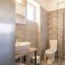 Oasis Tigaki bathroom with glass shower, sink, toilet, and mosaic tile wall in Tigaki