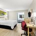 Days Inn by Wyndham Salina South guest room with bed, desk, chair, sofa, and view into adjoining bathroom