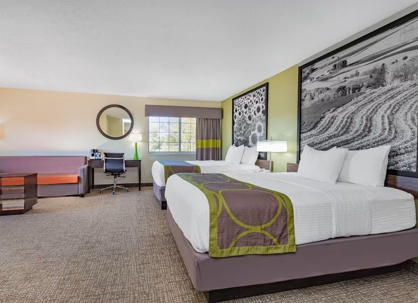 Emmetsburg Hotel & Suites guest room with two beds, desk, sofa and window in Emmetsburg