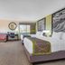 Emmetsburg Hotel & Suites guest room with two beds, desk, sofa and window in Emmetsburg