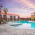 Wyndham El Paso Airport Hotel and Water Park pool at sunset in El Paso with palm trees and lounge seating