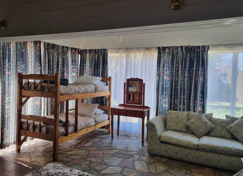 Emerald Guesthouse in Kempton Park room with bunk beds, sofa, table, and large window