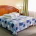 Grand Hotel Loja in Loja: guest room with a wooden bed, bedside lamps, and window with curtains