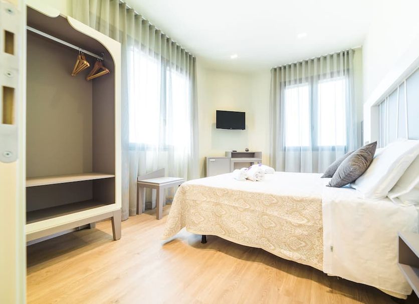 Hotel Calaluna room in Musile di Piave with bed, open wardrobe, and bright windows