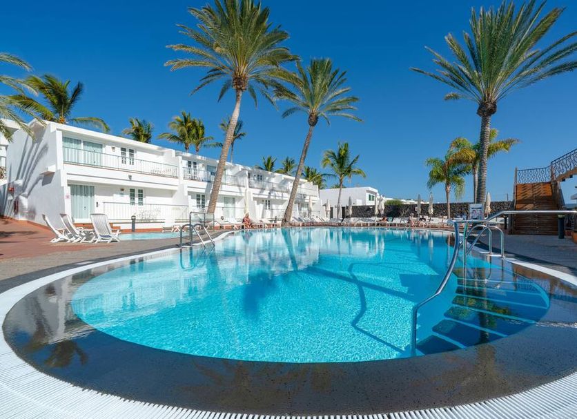 Plus Fariones Apartamentos in Puerto del Carmen with a palm-lined outdoor pool and sun loungers