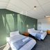 Oakwood Manor Motor Lodge in Mangere room with two single beds, green accent wall, and natural light