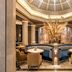 BLESS Hotel Madrid lobby seating area with round tables, curved banquette, and ornate dome ceiling