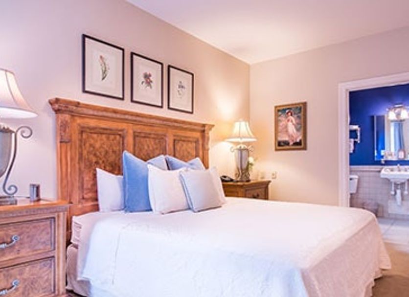 Brick Street Inn in Zionsville guest room with wood headboard, white bed and blue-accented bath doorway