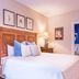 Brick Street Inn in Zionsville guest room with wood headboard, white bed and blue-accented bath doorway