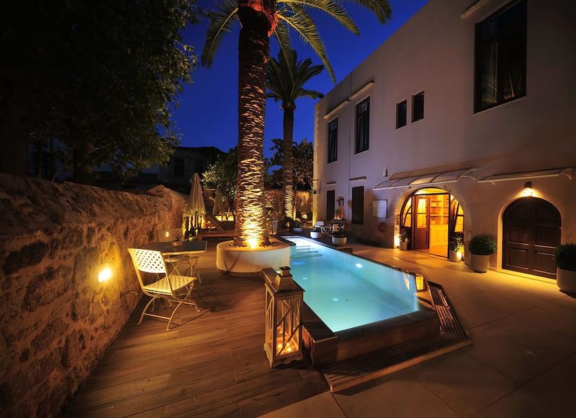 Pepi Boutique Hotel -Adults Only in Rethymno features a lit poolside courtyard at night with palm trees