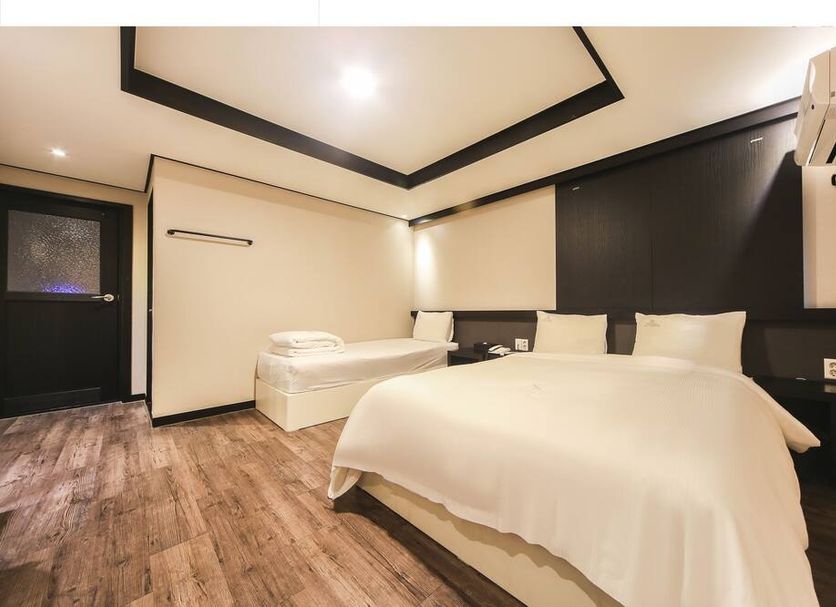 Elysee Hotel in Busan guest room with two beds, wood flooring, and dark accent walls