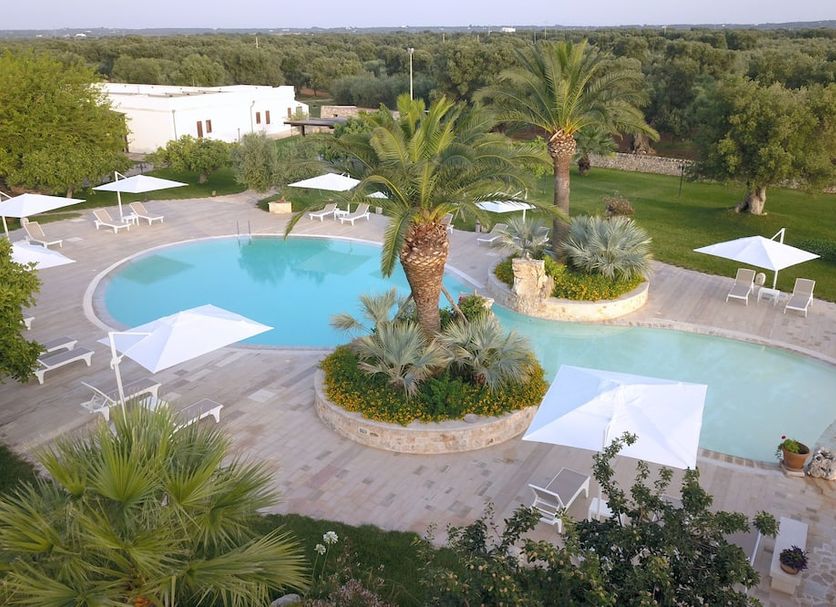 Masseria Valente in Ostuni with outdoor pool, palm trees, lounge chairs, and countryside views