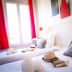 La Villa Andry in Ouistreham: twin hotel room with red curtains, bedside lamps, and tray on the beds