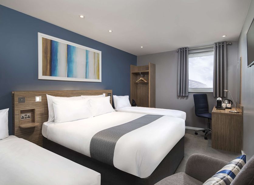 Travelodge London Twickenham guest room with triple beds, desk, window and wardrobe