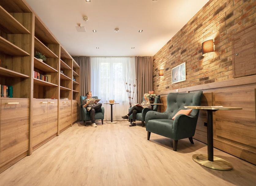 Bernstein Acamed Resort lounge in Neugattersleben with armchairs, bookshelves and brick wall