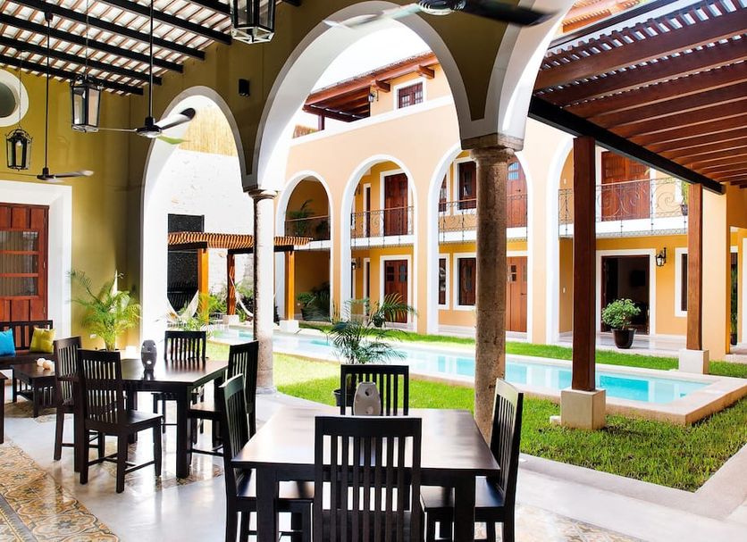 Boutique by The Museo in Mérida courtyard with dining tables beside a small pool and arched colonnade