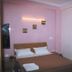 Hotel Landmark Haridwar guest room with double bed, pink walls, window AC and curtains