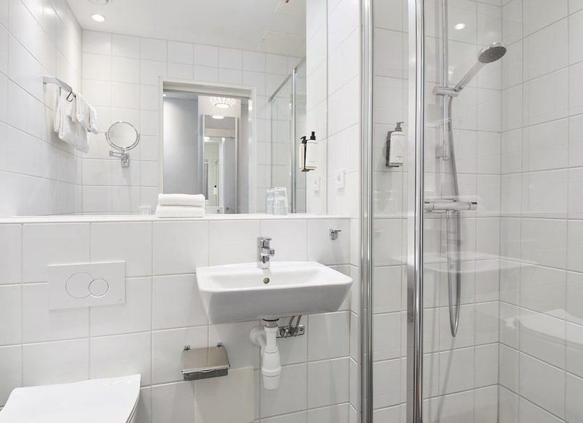 Ikea Hotell in Älmhult bathroom with walk-in shower, sink, and tiled walls