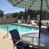 Triplodge of Santa Clarita pool with umbrella, lounge chairs and outdoor seating in Forest Park