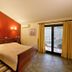 Agriani Hotel in Xánthi guest room with wooden bed, red accent wall, and balcony doors