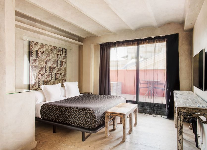 Arai Aparthotel Barcelona guest room with bed, TV, small table and balcony door