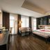 Ja Cosmo Hotel and Spa Hanoi guest room with king bed, seating area, dark wood floors and large windows