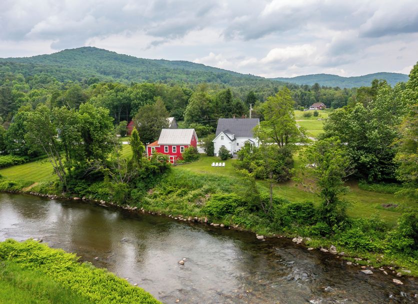 The Woodbridge Inn in Woodstock overlooking a river, green hills, and red and white houses
