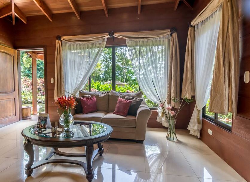 Hotel El Silencio del Campo in La Fortuna lounge with sofa, glass coffee table and garden-view windows